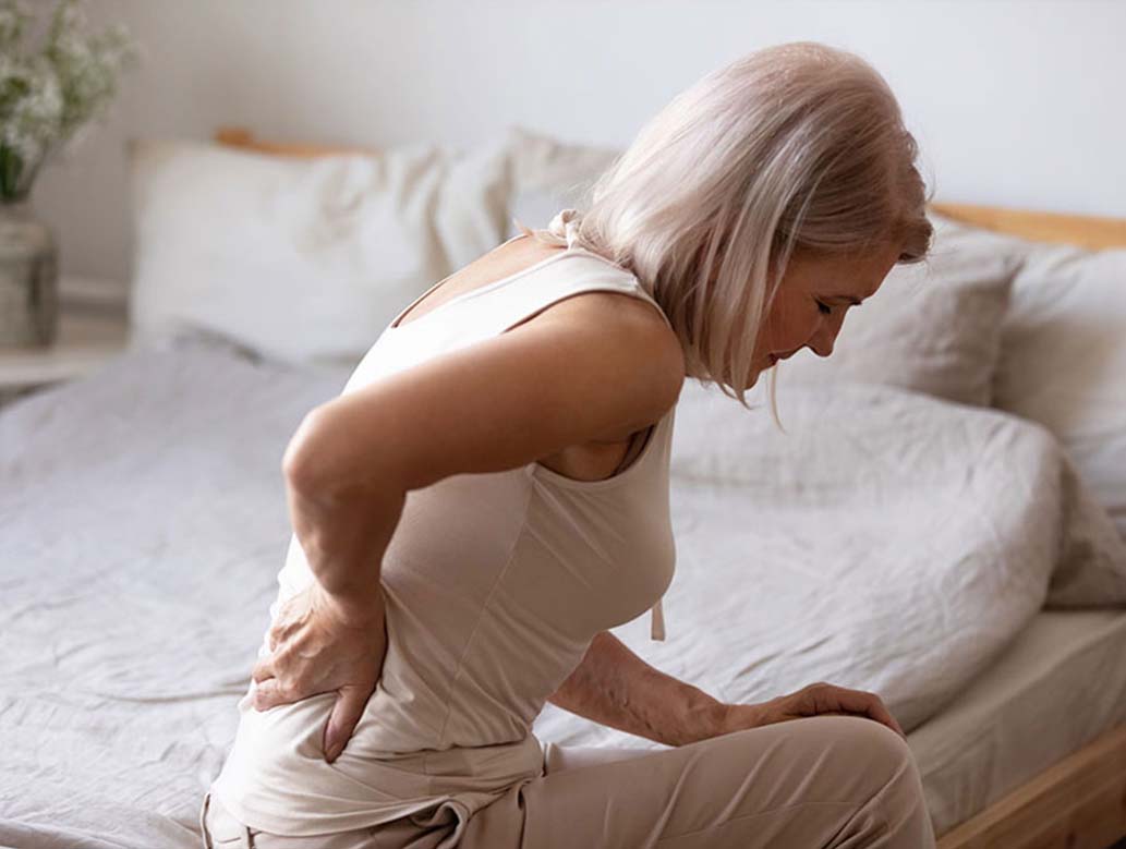 Woman sitting on her bed in pain from lumbar injury